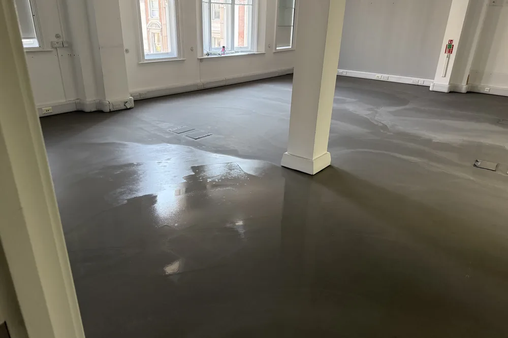 Latex screed poured level across a nursery floor before the vinyl went down