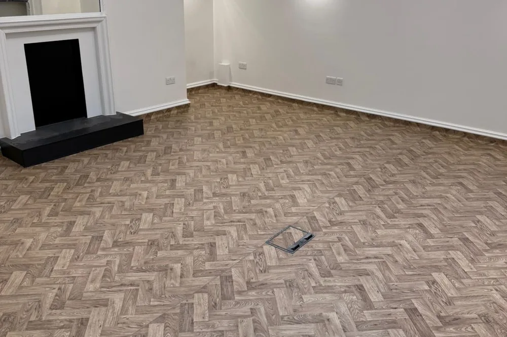 Herringbone flooring laid through a period room with a fireplace