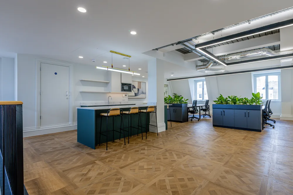 Wood-effect herringbone LVT through an open-plan London office with a kitchen island