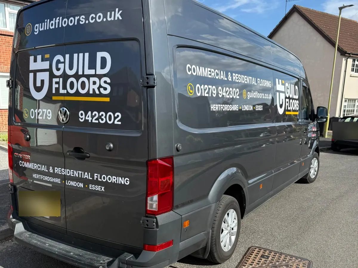 A dark grey VW Crafter van in Guild Floors livery with the G monogram, phone number and web address